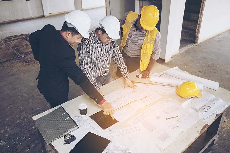 people looking at blueprints for a 2-floor pharmaceutical facility people looking at blueprints for a 2-floor pharmaceutical facility